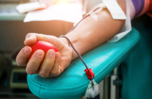 Close-up of a person's arm and hand as they donate blood.